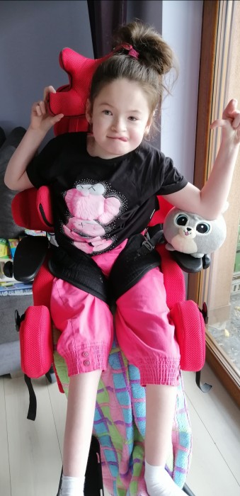 Uśmiechnięta dziewczynka na wózku inwalidzkim