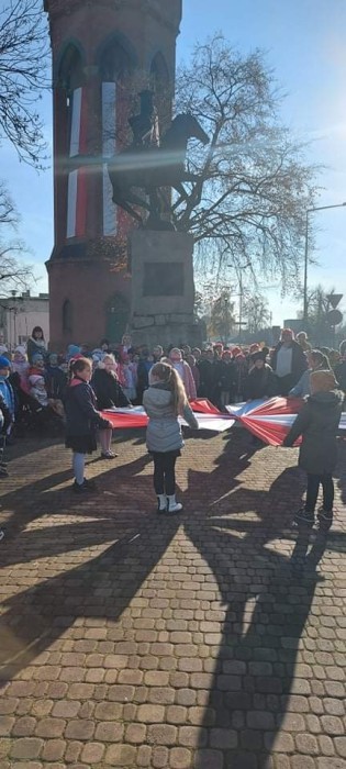 Uczniowie klas 1-3 przy pomoinku J. H. Dąbrowskiego podczas śpiewania hymnu.