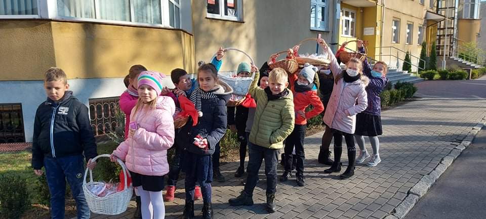 Uczniowie klas 2 specerują ulicami mista, by czestować mieszkańców cisteczkami w barwach narodowch.
