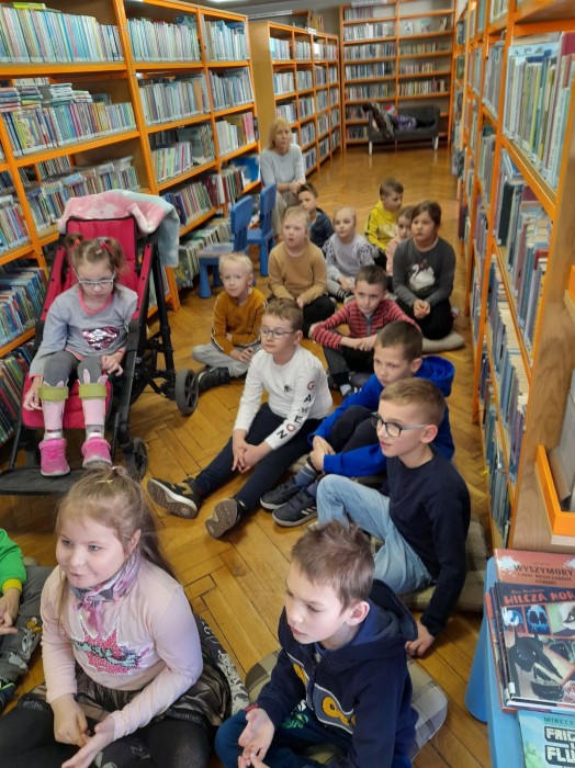 uczniowie klasy 1c z wizytą w Bibliotece Publicznej- słuchają Pani Bibliotekarki